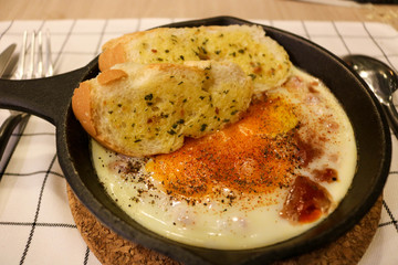 Fried egg on pan with garlic bread
