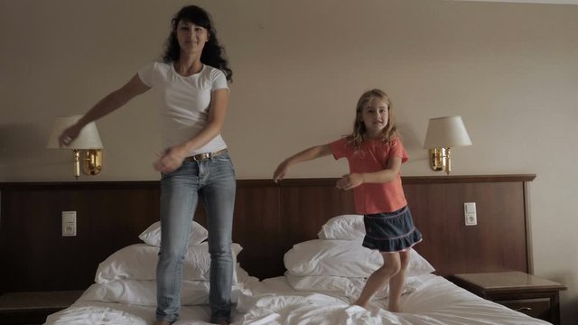 Happy Little Girl And Women Dancing Have Fun In Bedroom. Happy Family Of Cute Daughter And Young Mother Jumping Dancing On Bed At Home. Floss Dance Viral. Mother Her Daughter Playing At A Bedroom.