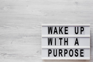 'Wake up with a purpose' words on a modern board on a white wooden background, top view. Overhead,...
