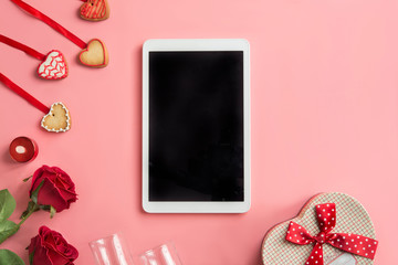 tablet and roses,  on pink background. top view.