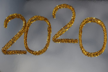 New year 2020 inscription made of glittering tinsel with a silver background.