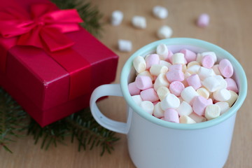 Container with marshmallows and red gift box on the wooden table - Christmas holidays