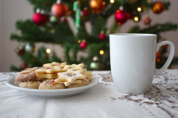 Cup of coffee and cookies in front of Christmas tree