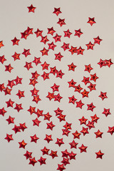 Red shiny stars on a light background. Festive composition.