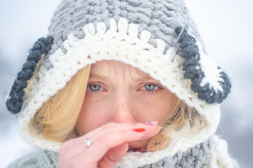 Portrait of Young woman having flu and blowing her nose. Young woman with nose wiper near winter tree. Woman with napkin sneezing in the winter snowy park.