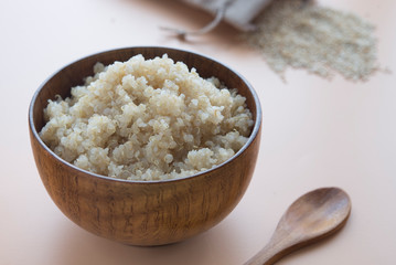  cooked quinoa in bowl and wooden spoon on brown background