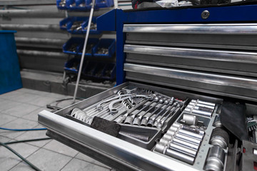 A set of tools from wrenches and heads for unscrewing nuts and bolts in a special cabinet or blue workbench for repair in a car service or at a factory. Industry and manufacturing.