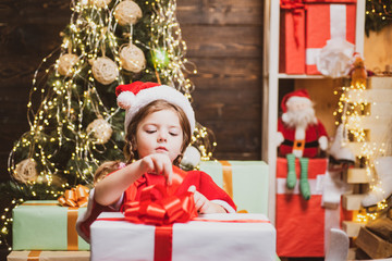 Happy child decorating Christmas tree. Models child having fun with gift. Child with gift. The morning before Christmas. Kids enjoy the holiday.