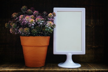 Blank Display frame stand with artificial plant home decoration on wooden background