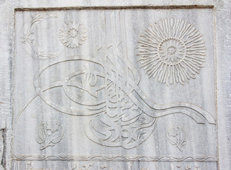 fragment of a gray stone wall depicting oriental patterns hieroglyphs