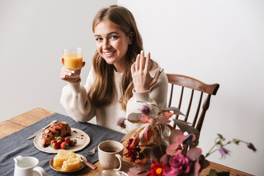Image of happy caucasian woman smiling while having breakfast