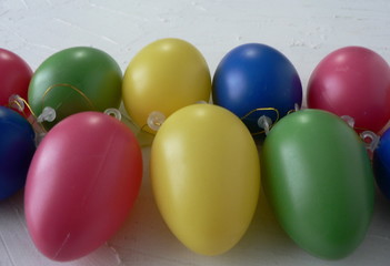 Multicolored decorative easter eggs frame border on a white textured background. Copyspace for text. 