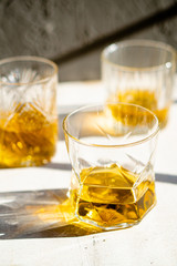 Whiskey in glasses on table in bright sunlight, yellow drink