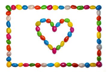 Frame of colorful candies isolated on white background with multicolor heart of candy