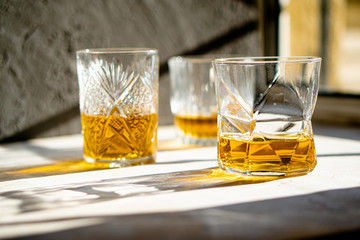 Whiskey in glasses on table in bright sunlight, yellow drink