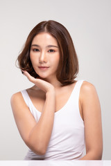 Beautiful Asian young woman touching soft cheek smile with clean and fresh skin Happiness and cheerful with positive emotional,isolated on gray background,Beauty and Cosmetics Concept