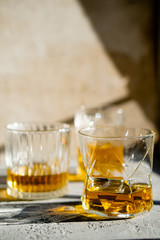 Whiskey in glasses on table in bright sunlight, yellow drink