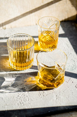 Whiskey in glasses on table in bright sunlight, yellow drink