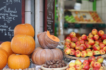 Orange ripe pumpkins, chestnuts and red yellow apples on the autumn market in Paris. October, harvest season in France. Close up, front view - Powered by Adobe