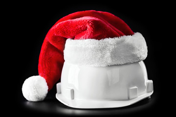 Santa Claus helper hat on white building helmet. Isolated on black background