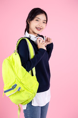 Asian student with backpack and headphone on pink background.