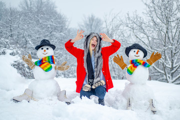 Happy girl winter portrait. Happy snowman standing in winter Christmas landscape. Winter woman in...