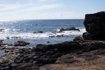 Deep blue water with waves, white foam and volcanic rocks