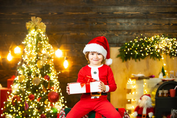 Kids enjoy the holiday. Christmas child holding a red gift box. Christmas decorations. Funny kid holding Christmas gift.