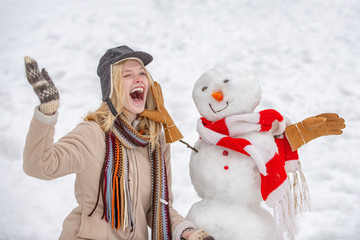 Cute girl making snowman on snowy field outdoor. Funny winter girl playing with snow in park on...
