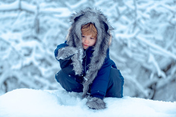 Fototapeta na wymiar Winter portrait of cute child in snow Garden. Joyful child Having Fun in Winter Park. Children in winter park. Kids winter portrait.