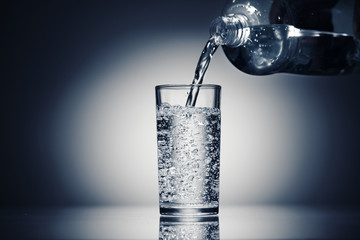 pouring sparkling water in a glass on a dark blue background