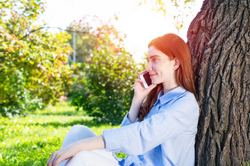 Young redhead woman talking on smartphone