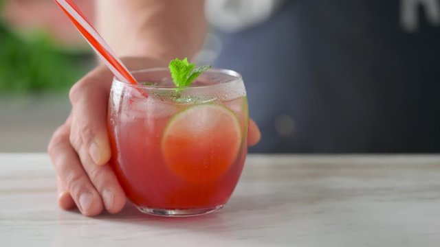 Male hand puts on the table a glass of refreshing summer drink. Cold watermelon drink with lime and mint. Watermelon Smoothie