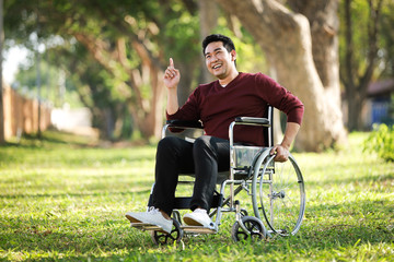 Asian Young Man sitting on the wheelchair in the park hospital