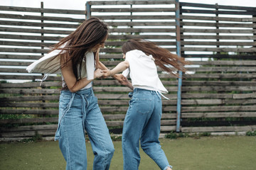 Portrait of Two Young Brunette Twins Sisters Dressed Alike in Jeans and White T-shirt, Best Friends Forever Concept