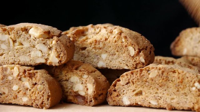  A female hand puts a Cantucci biscuit on a hill of cookies on a black background.