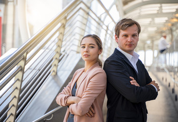 Concept of partnership in business. Young man and woman standing back-to-back with crossed hands against
