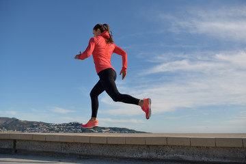 Fototapeta na wymiar Sportswoman runs on the promenade near the sea