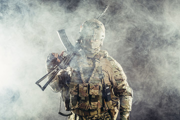 portrait of young army soldier in action with gun, dark and foggy background