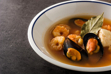 French bouillabaisse soup in white plate on black background. 