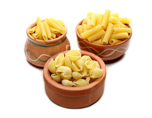 Conchiglie grandi, penne rigate and tortiglioni pasta in clay pot, bowl isolated on white background