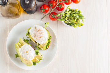 Avocado toast, cherry tomato and poached eggs on wooden background. Breakfast with vegetarian food, healthy diet concept.