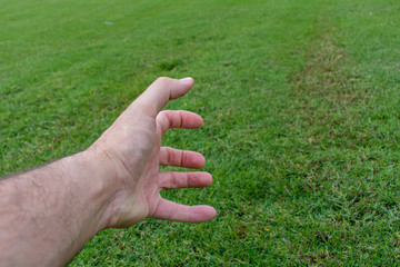Conceptual agony fist and hand on green grass. Struggling, pain, frustrated concepts.