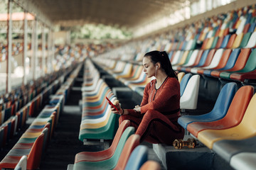 Portrait of One Sports Fitness Girl Dressed Fashion Sportswear Outfit Using Smartphone at the City Stadium, Healthy Lifestyle Concept