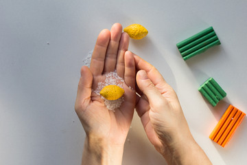 Small lemon made from polymer clay with sea salt to make dents as on real lemon fruit in woman...