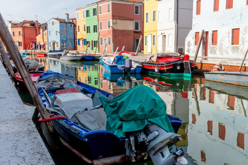 Fototapeta na wymiar Burano, Venice / Italy - 08 25 2018: View of small boats on the water with reflections of the houses