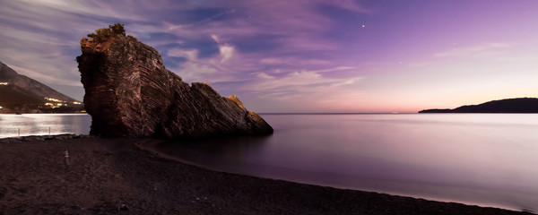 night landscape cliff dark blue sea purple sky and moonlit path. Sunset sea romantic landscape with bright saturated colors, rock stones.