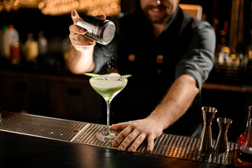 Bartender sprinkles drink with eucalyptus and slice of lemon