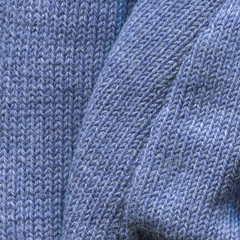 Blue knitted pullover background, close up. Knitted cloth texture of Princess Blue Color yarn. Fine-knit pure cashmere jumper. Soft blue angora background, closeup. Folded sweater, pleats