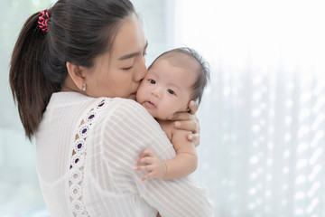 Young mother holding her baby. Portrait of Asian young with her happy child on arms on white background.